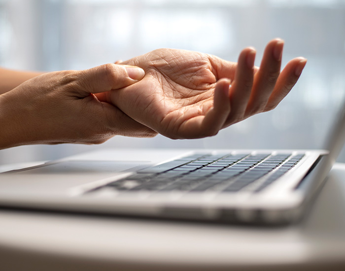 Woman massaging painful wrist at work