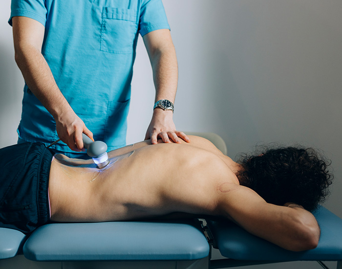 doctor using laser therapy while patient lying on stomach